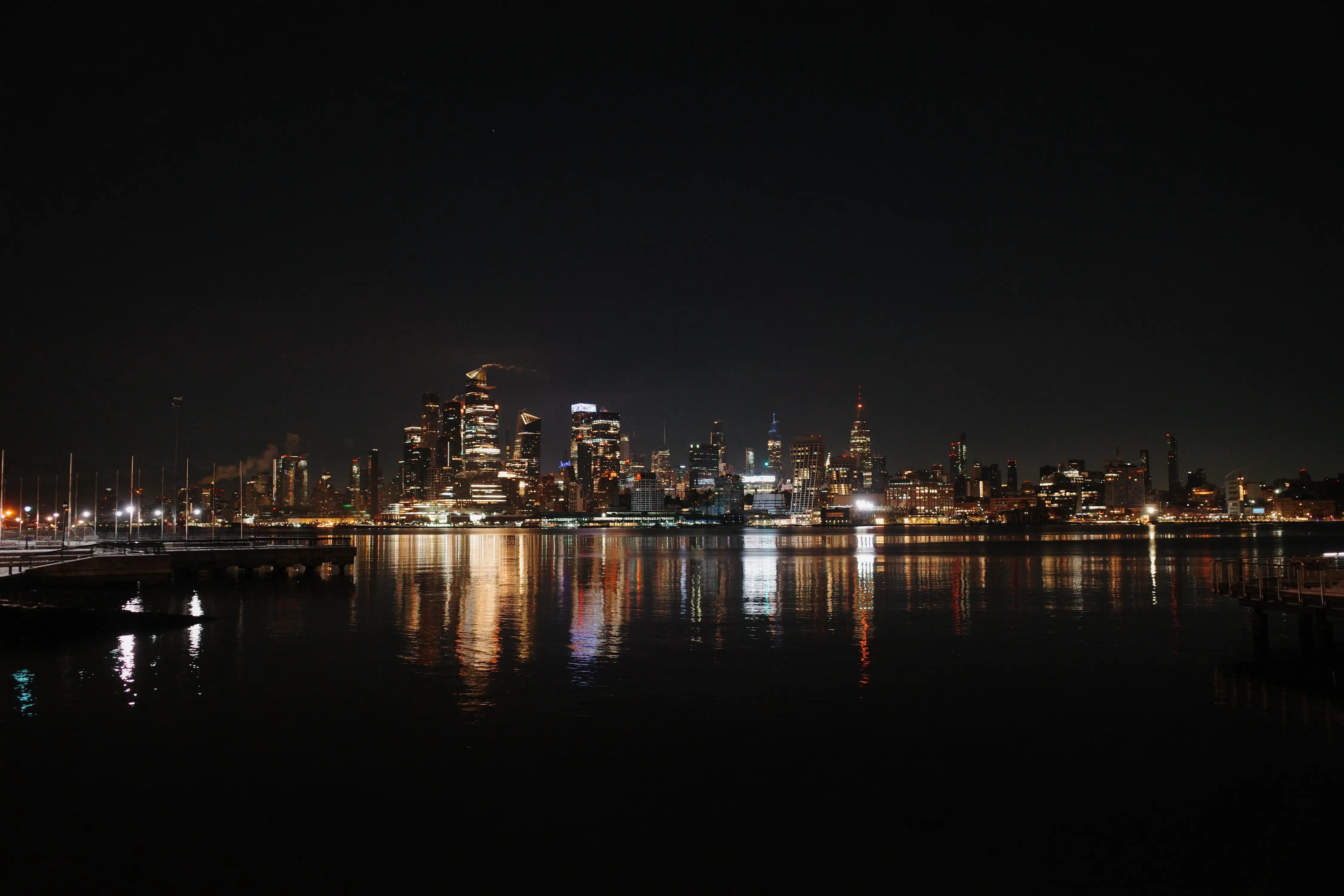 The Manhattan skyline reflected across the water at night